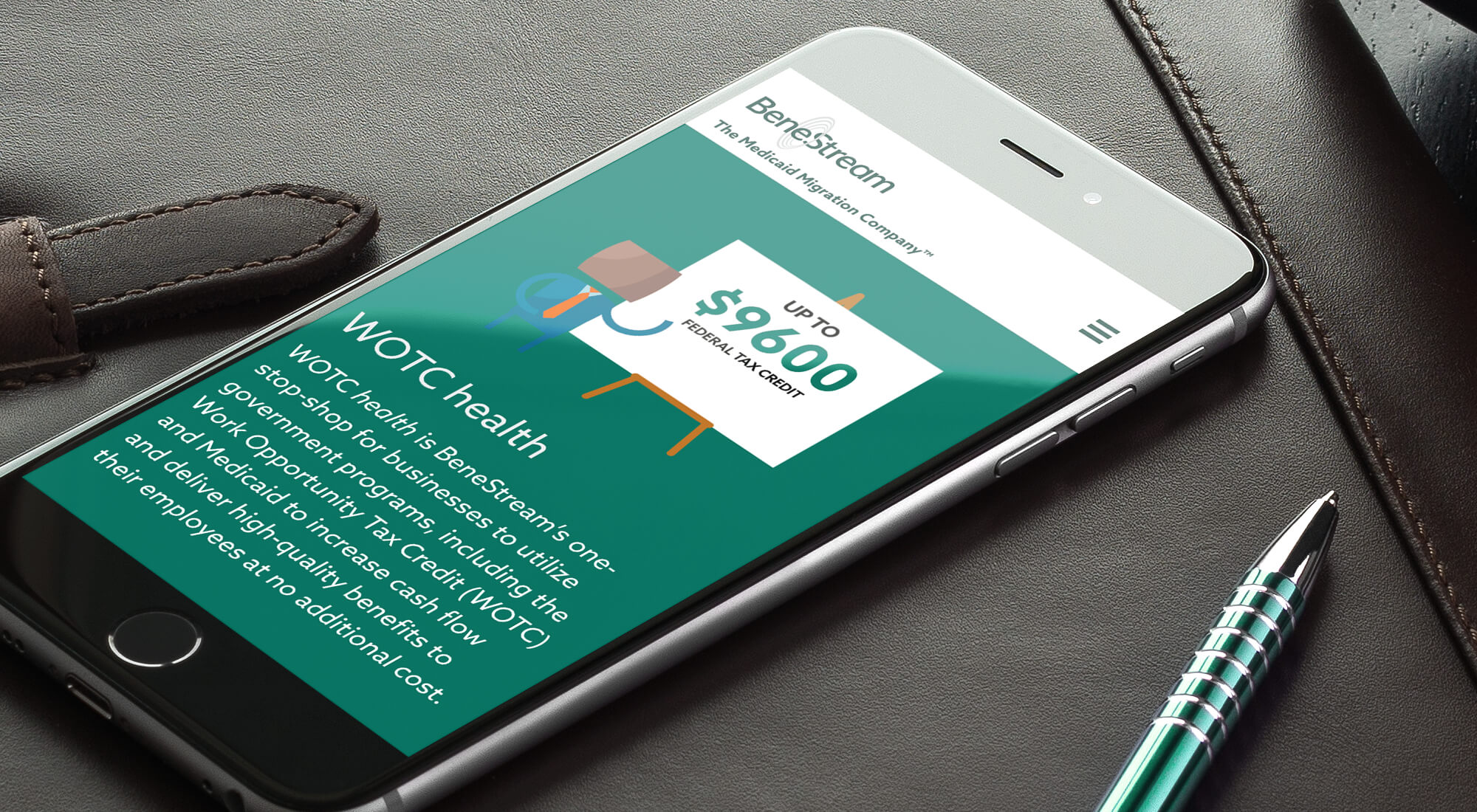 A smartphone on a desk displays a webpage about WOTC health on the BeneStream website, next to a closed leather notebook and a pen.