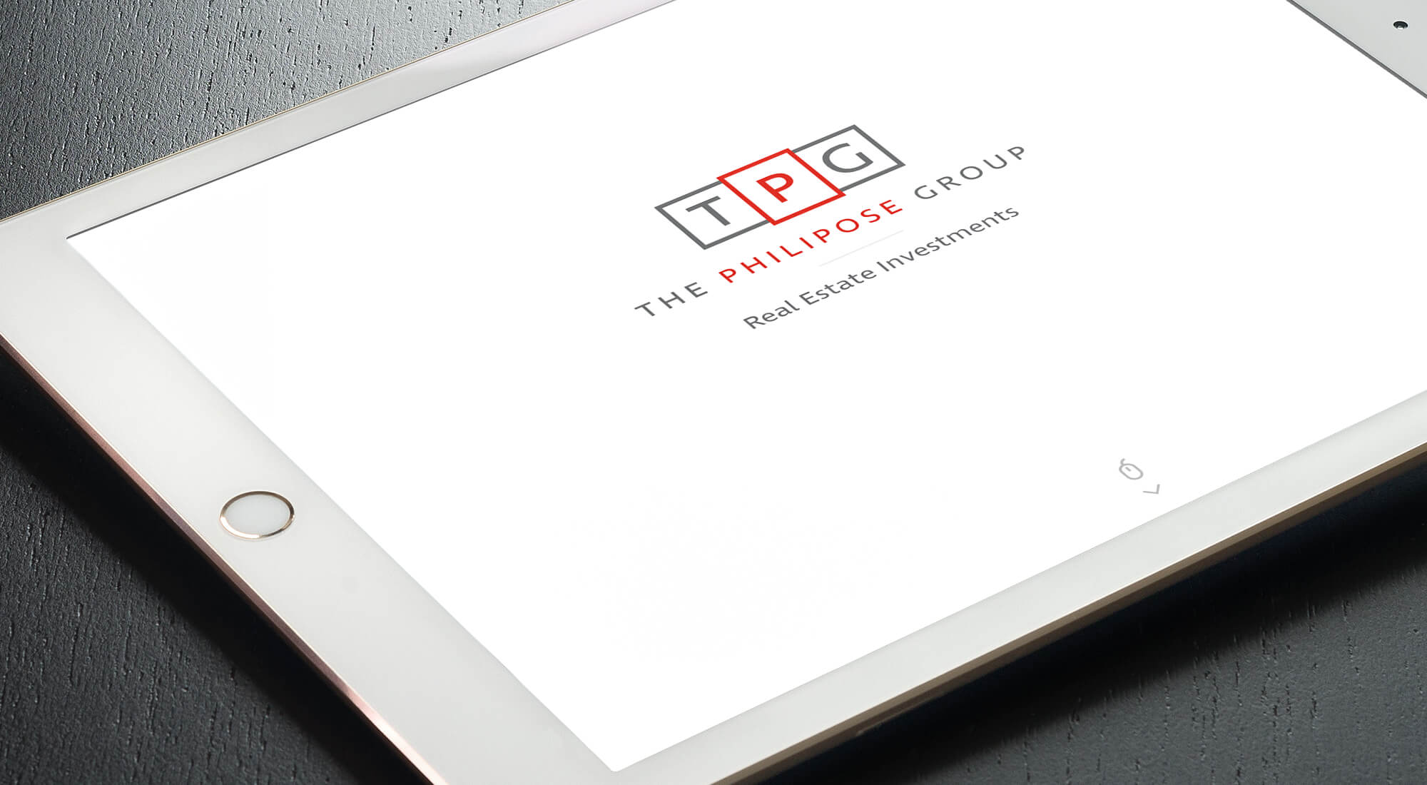A tablet displaying the logo and text for The Philipose Group, a real estate investment company, on a white screen.