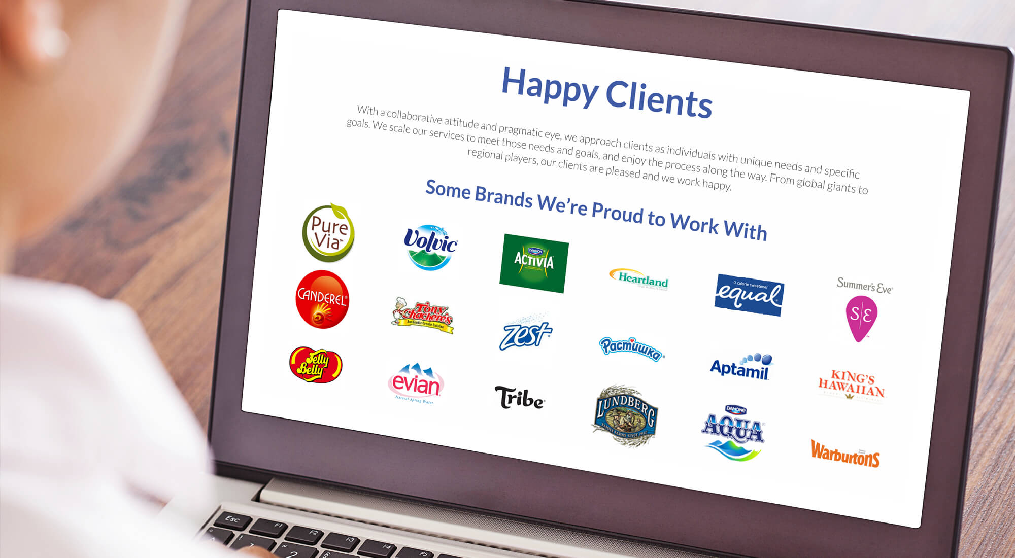 A person looks at a laptop screen displaying a "Happy Clients" page with various food and beverage brand logos and text highlighting client satisfaction.