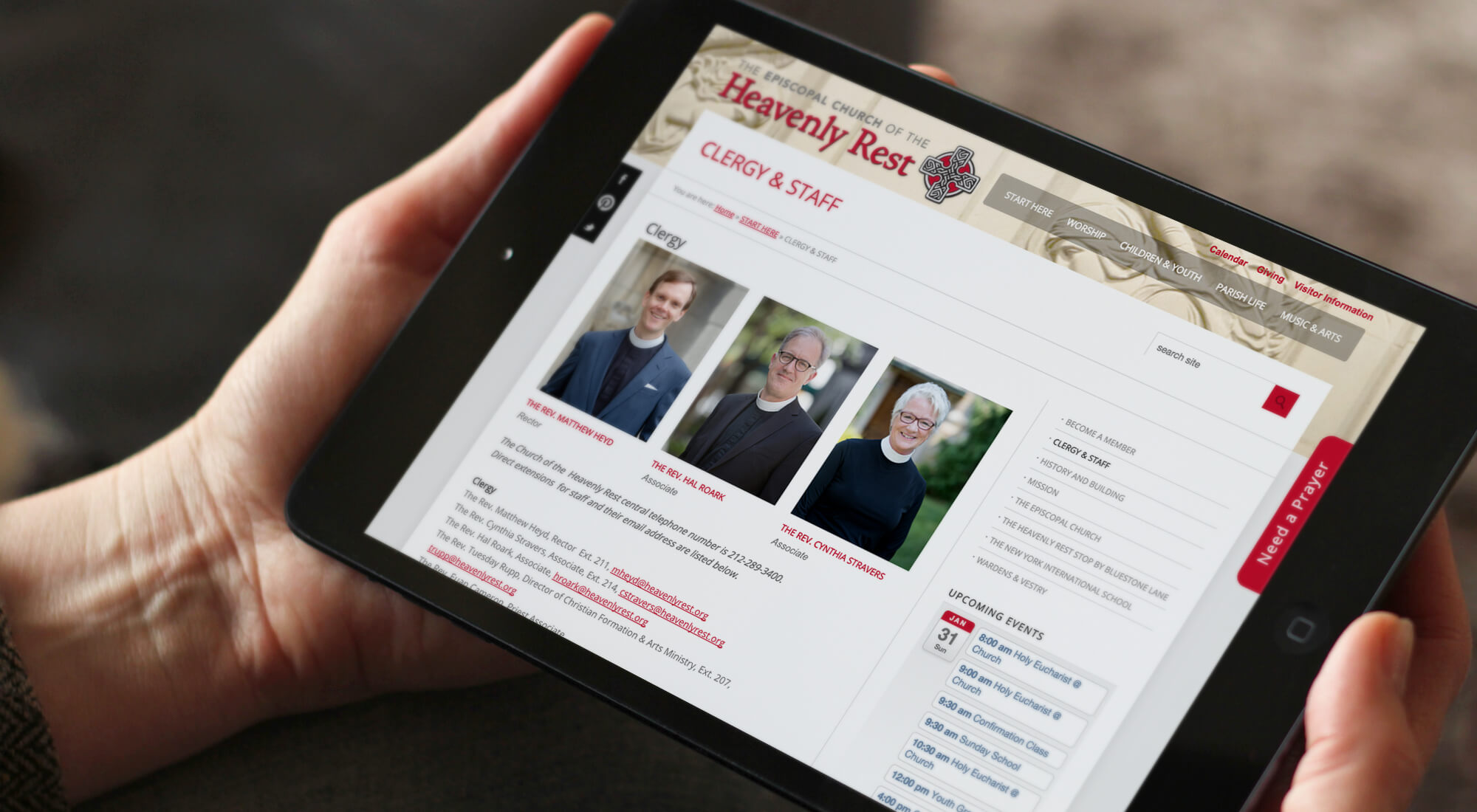 Person holding a tablet displaying a church website with clergy and staff photos and contact information.
