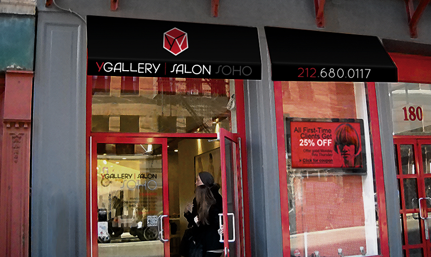 A person with long hair enters Y Gallery Salon Soho, a hair salon with glass doors and black awnings displaying the salon name, logo, phone number, and a 25% off sign for first-time clients.