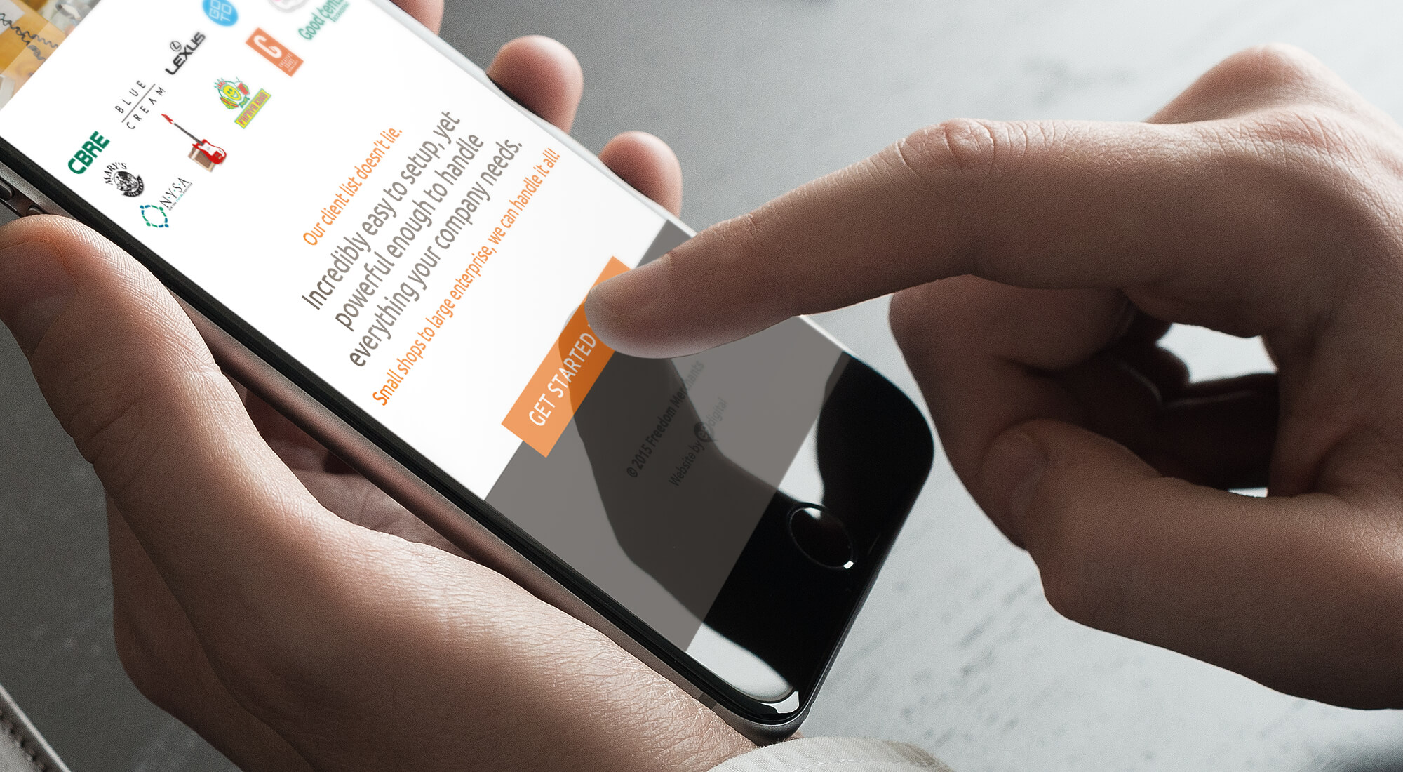 A hand holding a smartphone, finger touching the screen, which displays a "Get Started" button on a website with logos and text.
