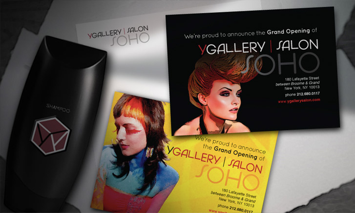 A black shampoo bottle and two grand opening flyers for YGallery Salon Soho are displayed on a surface, featuring stylized portraits and the salon's address details.