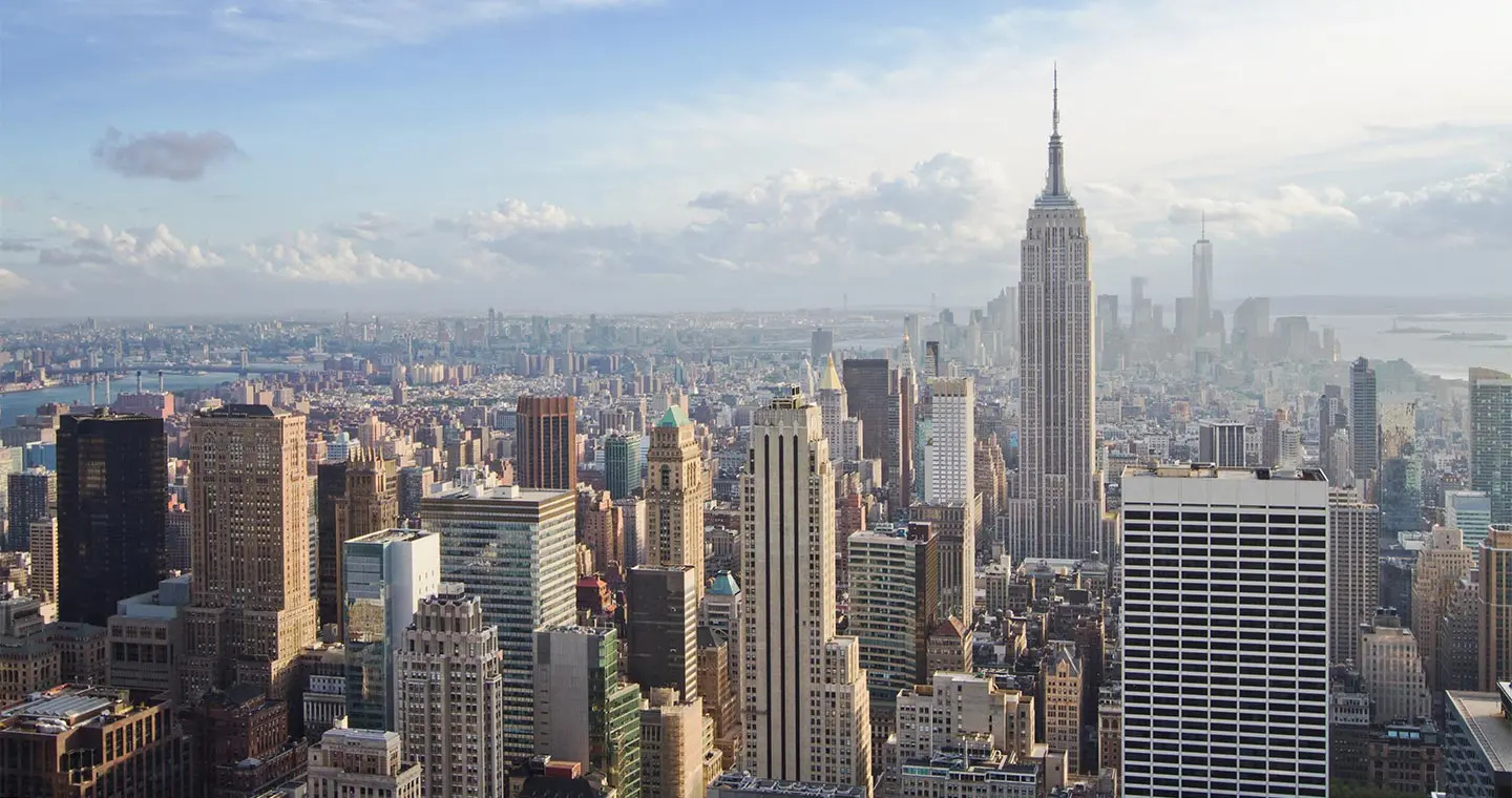 Aerial view of the New York City skyline featuring the Empire State Building and surrounding skyscrapers, reminiscent of estate planning website design that captures both grandeur and clarity under a partly cloudy sky.