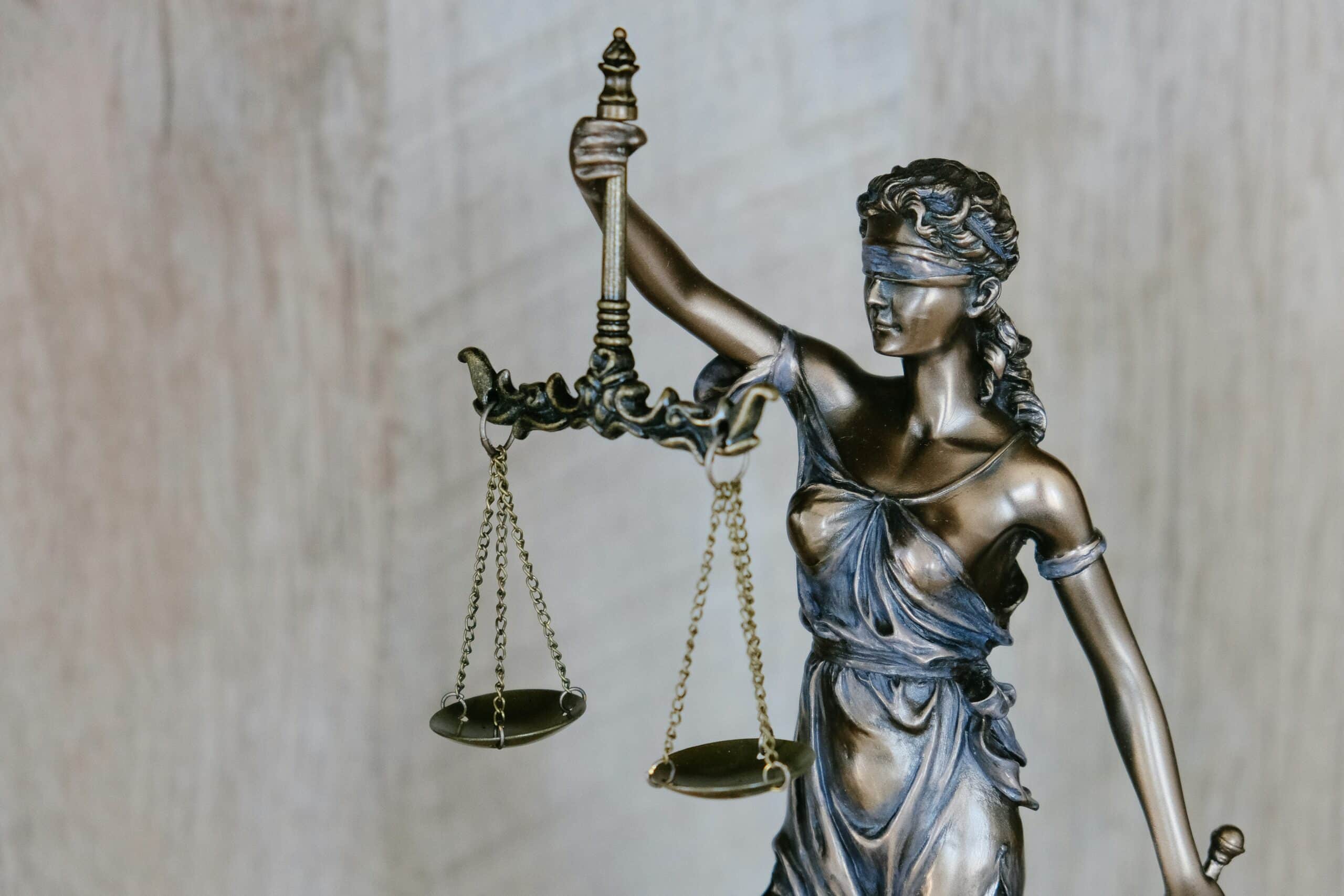 A bronze statue of Lady Justice, symbolizing fairness, stands blindfolded and holding balanced scales and a sword—an iconic image often found in the office of an NYC Attorney.