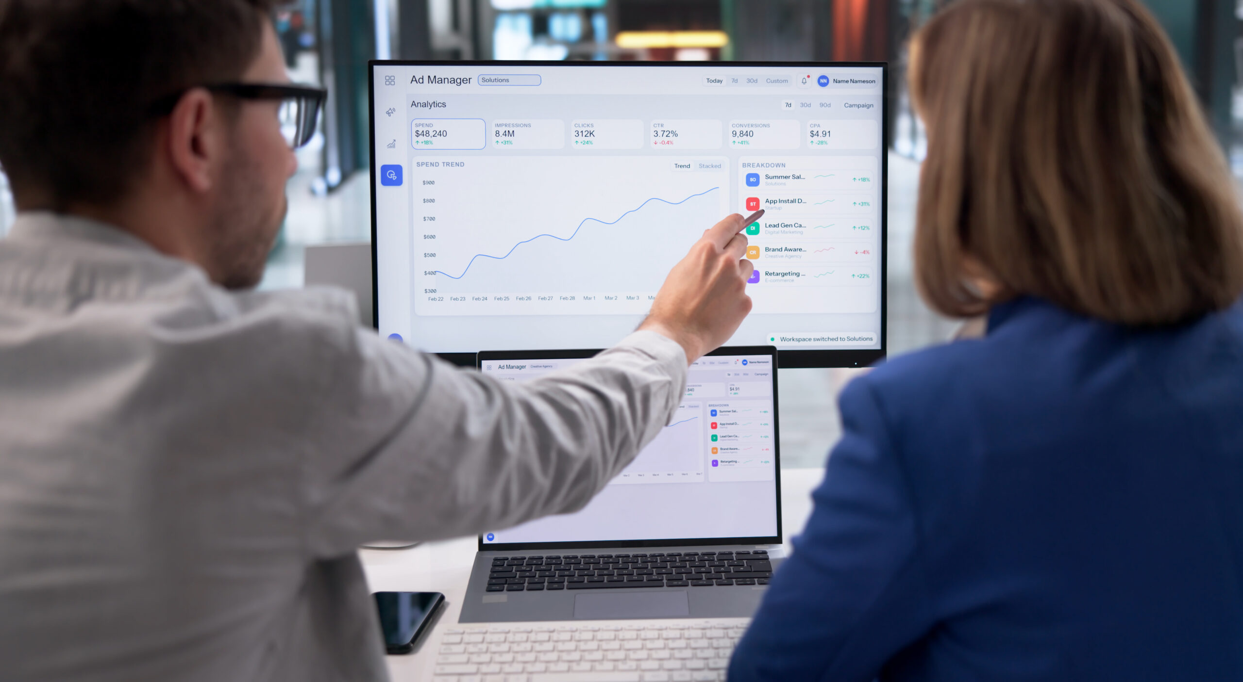 Two people look at a computer screen showing a line graph and analytics dashboard, with one person pointing at the upward trend on the monitor—highlighting successful PPC For Lawyers campaign performance.